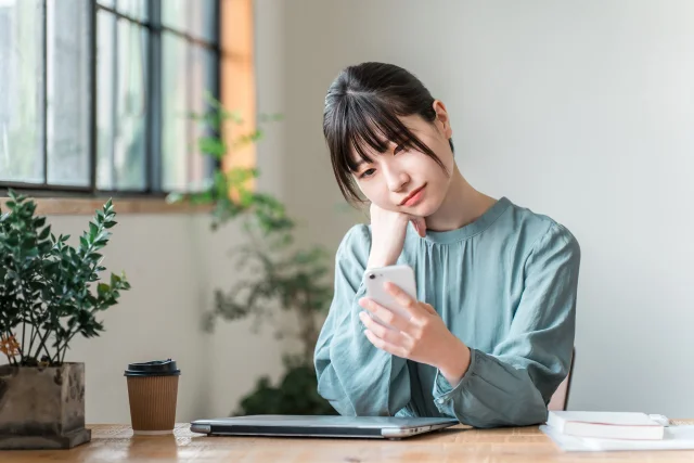 困った顔でスマホを見る人