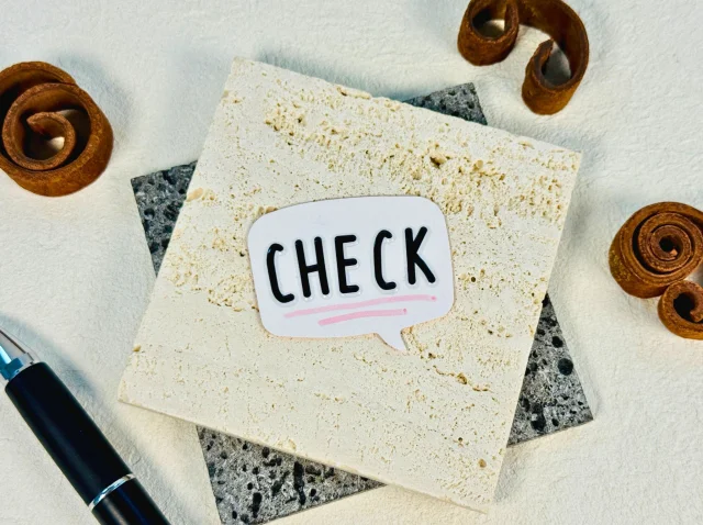 四角い板の上に、吹き出し型に切られ「CHECK」と書かれた紙が置かれている