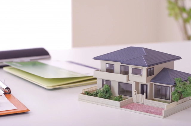 テーブルに家の模型と書類が置かれている