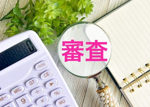 住宅ローン本審査のイメージ(ノートと計算機と、審査と描かれた虫眼鏡)