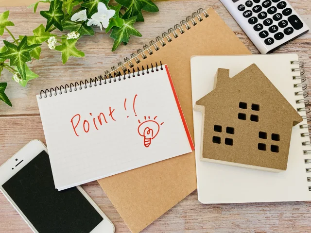 テーブルにスマホと家の模型、「Point！」と書かれたスケッチブックが置かれている