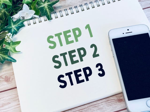 スマホが乗ったスケッチブックに「STEP 1」「STEP 2」「STEP 3」書かれている。